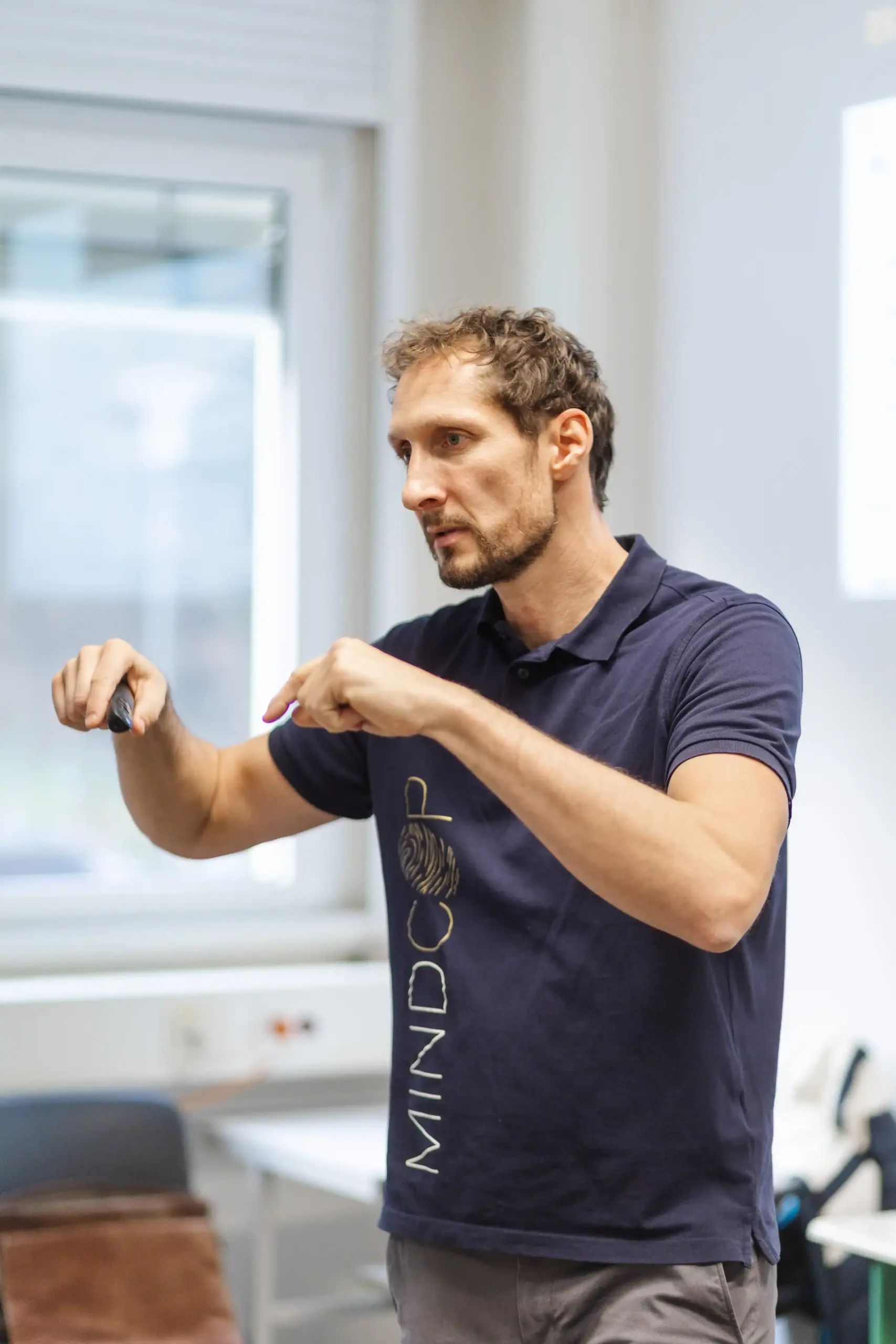 Marco Winzer im Profil deutet mit beiden Fingern auf den Boden vor sich im Deeskalationstraining